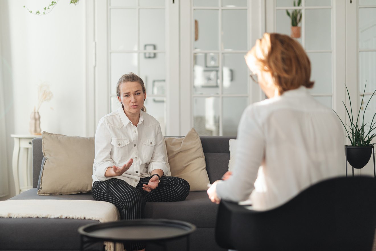 Woman in White Long Sleeves Sitting on Gray Sofa 